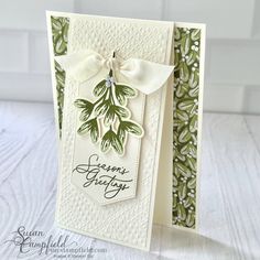 a close up of a greeting card with a bow on the front and green leaves on the back