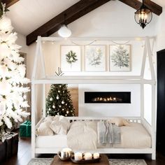 a white bed sitting in a bedroom next to a christmas tree with lights on it