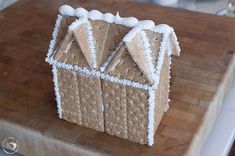 a gingerbread house with icing on a cutting board