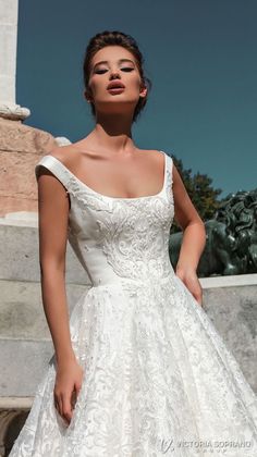 a woman in a white wedding dress standing next to a statue with her hand on her hip