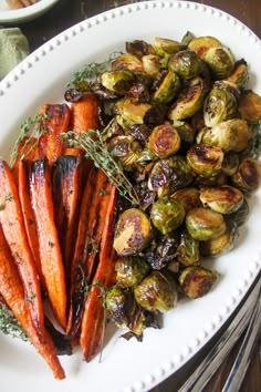 roasted carrots and brussel sprouts on a white plate with silverware