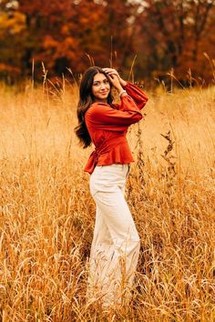 a woman standing in tall grass with her hands on her head