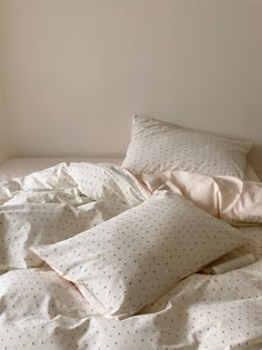 an unmade bed with white sheets and polka dot pillow cases on top of it