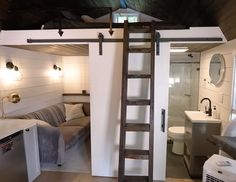 a loft with a ladder leading up to the bathroom and living room area in it