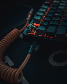 a close up of a computer keyboard with a cord attached to the key board and plugged in