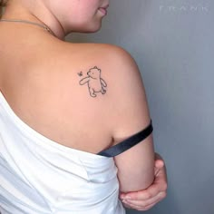 a woman with a small tattoo on her shoulder holding onto the back of her arm