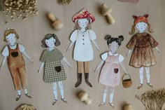 paper dolls are arranged on a table with mushrooms and other items in the foreground