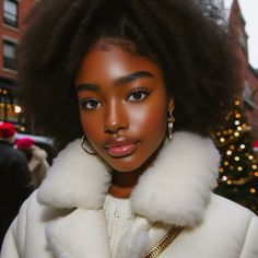 a woman with an afro is standing in front of a christmas tree wearing a white coat