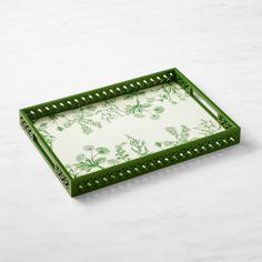 a green and white tray with floral designs on it, sitting on a marble surface