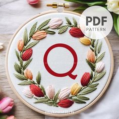 an embroidery pattern with the letter q on it, surrounded by flowers and tulips