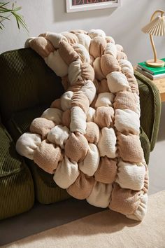 a couch covered in pillows on top of it's back cushion, with a green chair next to it