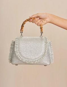 Cult Gaia Ozzy Mini Top Handle Bag in silver. Bamboo top handle. Woven raffia body. Fringe trim. Silver toned purse feet. Metallic coated raffia. W 3.94" X H 5.71" X L 8.66". HANDLE DROP: 2.91". 52% Cotton, 48% Polyamide. Trim: 100% Cow Leather. Lining: 90% Polyester, 10% Polyurethane. Imported. Silver Shoulder Bag For Summer Shopping, Silver Shoulder Bag For Summer, Silver Top Handle Shoulder Bag For Shopping, Silver Crossbody Bag With Handle Drop, Silver Party Bag With Round Handle, Silver Shoulder Bag With Top Carry Handle, Chic Silver Shoulder Bag With Round Handle, Silver Handheld Shoulder Bag With Top Carry Handle, Silver Top Handle Shoulder Bag