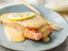 a piece of salmon covered in gravy on a blue plate with a fork