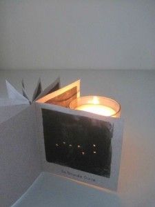 a lit candle is in the corner of a paper box that looks like an origami bird