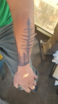 a man with a forest tattoo on his arm