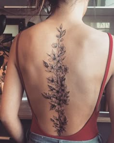 the back of a woman's neck with flowers on it and leaves coming out