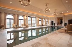 a large indoor swimming pool with chandeliers and windows in the back ground area