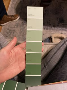 a hand holding a pantone color swatch in front of a person's feet