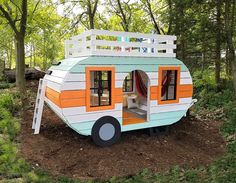 a tiny house made out of wood and painted orange, white and blue with a ladder on the roof