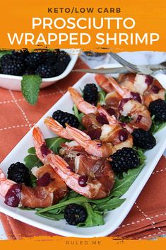 a white plate topped with shrimp and blackberries on top of a red table cloth