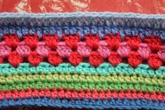 a crocheted dishcloth with multicolored stripes on the bottom and sides