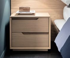 a nightstand with two drawers next to a bed