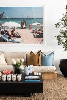 a living room filled with lots of furniture next to a painting on the wall above a coffee table