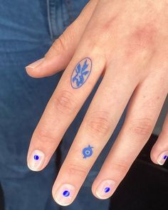 a woman's hand with blue nail polish and an evil eye tattoo on it