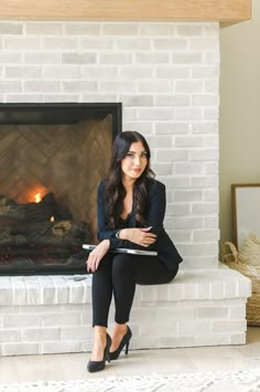 a woman sitting in front of a fire place