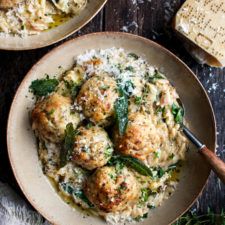 two plates with meatballs, rice and parmesan cheese on them next to bread