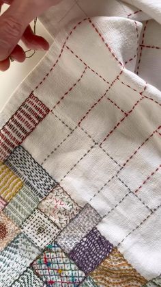 someone using scissors to sew on a patchwork piece of cloth that has been stitched together