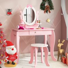 a pink desk with a mirror, stool and christmas tree in front of the wall