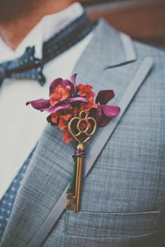 a boutonniere with an orange and red flower attached to the lapel of a suit