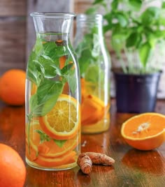 oranges, lemons and basil in glass bottles on a table