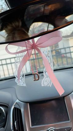 a pink ribbon tied to the dash board of a car with a letter d on it