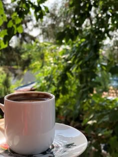 a cup of coffee sitting on top of a white saucer next to a window