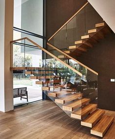 a wooden stair case with glass railing and wood handrails in a modern home