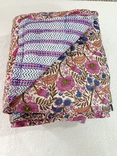 three pieces of cloth folded on top of each other in different patterns and colors, sitting on a white surface