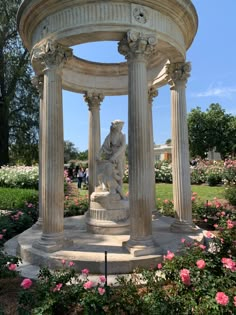 an outdoor fountain surrounded by flowers and greenery