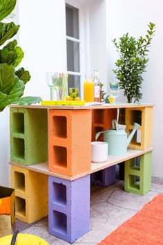 an outdoor table made out of cinder blocks with plants in the corner and cups on top