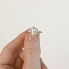 a woman's hand holding an engagement ring with two diamonds on it and the middle finger