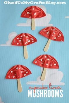 four red paper fans with hearts on them sitting in the middle of a blue background