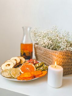 a plate with orange slices and crackers on it next to a vase filled with baby's breath