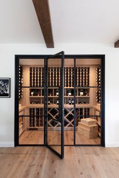 an open wine cellar with wooden floors and black glass doors that lead into the room