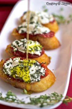 small appetizers with cheese and sauces on a white plate sitting on a red table cloth