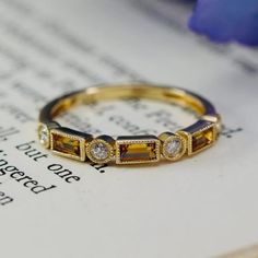 a close up of a ring on top of an open book with flowers in the background