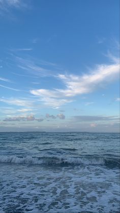 an ocean view with waves crashing on the shore and blue sky in the back ground