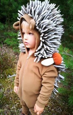 a young child wearing a costume made out of toothpicks on his head is standing in the grass