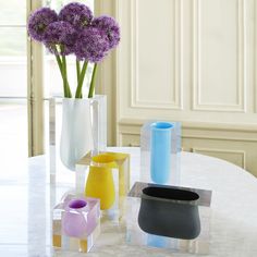 three vases with flowers in them sitting on a table next to each other,