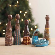 five wooden peg dolls lined up in front of a christmas tree